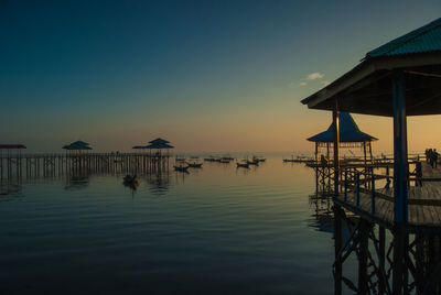 Pier on sea against clear sky during sunset