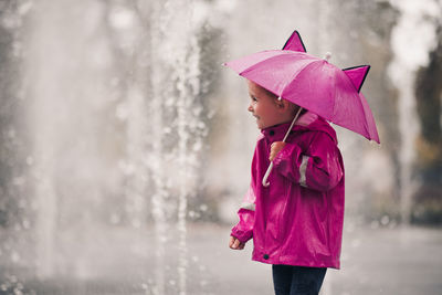 Cute girl holding umbrella in rain