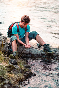 Boy sitting at riverbank