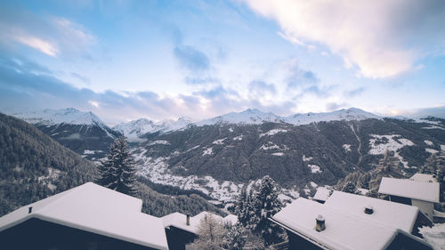 Houses by mountains against sky during winter