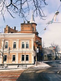 Empty road by buildings against sky during winter