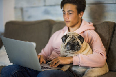 Midsection of man using mobile phone while sitting on sofa
