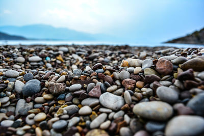 Close-up of pebbles on beach against sky