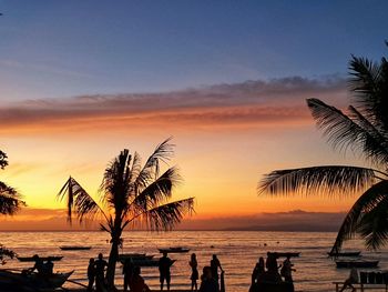 Silhouette palm trees on beach against sky during sunset