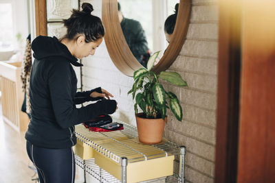 Woman checking diabetes kit while standing in front of mirror at home