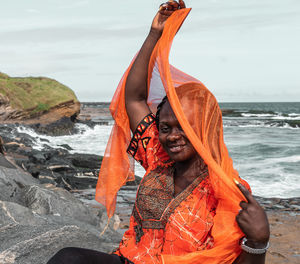 African woman with orange dress on the cliffs by the sea in sekondi-takoradi ghana west africa