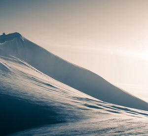 Scenic view of sea by mountain against sky