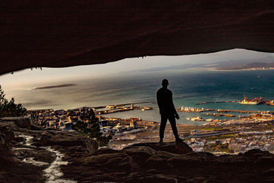 Rear view of man standing on rock by sea