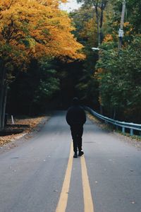 Rear view of man walking on road