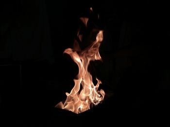 Close-up of burning candle against black background