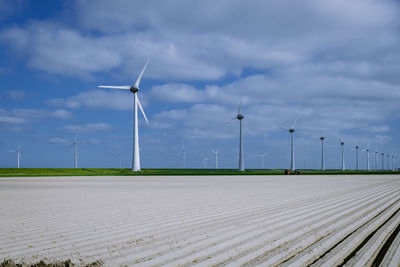 Wind turbines on field against sky