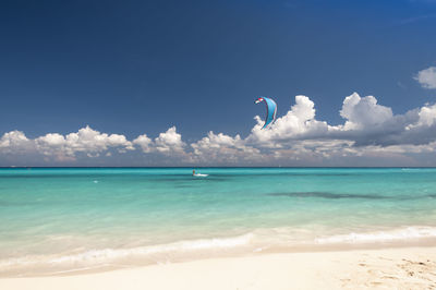 Kitesurfer caucasian man with kiteboard in front of an amazing and deserted tropical beach