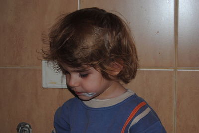 Portrait of boy standing against wall at home