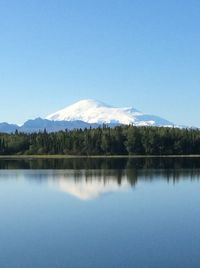 Scenic view of lake and mountains against clear blue sky