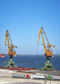 Crane at commercial dock against clear blue sky