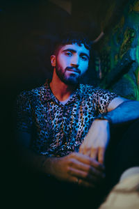 Portrait of confident bearded man sitting at illuminated bar