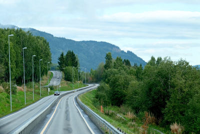 Road amidst trees against sky