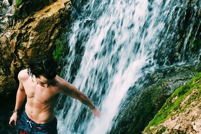 High angle view of shirtless man standing at waterfall