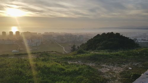 Scenic view of landscape and buildings against sky during sunset