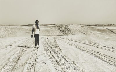 Full length rear view of woman walking on sand in desert