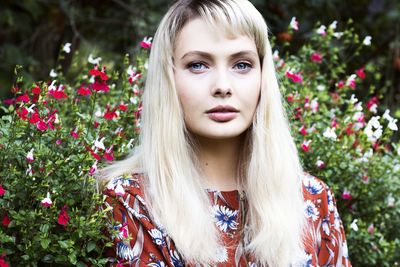 Portrait of beautiful woman with blond hair standing by plants in park