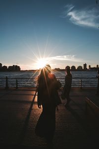 Silhouette woman on promenade against sky during sunset