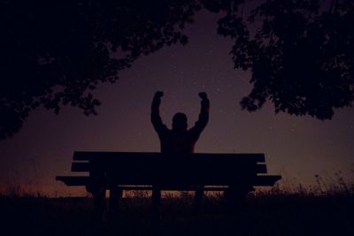 Silhouette man sitting on bench at night