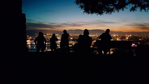 Silhouette people at beach against sky during sunset