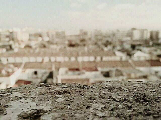 built structure, architecture, building exterior, focus on foreground, selective focus, surface level, close-up, sky, city, day, outdoors, water, cityscape, stone - object, no people, beach, textured, nature, focus on background, river