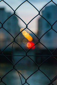 Full frame shot of chainlink fence against sky during sunset