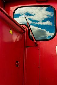 Close-up of cloudy sky seen through red vehicle
