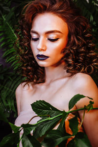 Beautiful redhead woman wearing make-up by plants