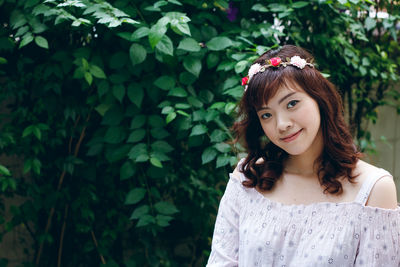 Portrait of a beautiful young woman standing against plants