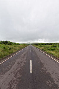 Road amidst field against sky