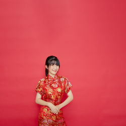 Woman standing against red background