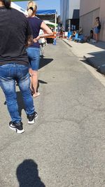 Rear view of people standing on street in city