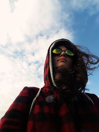 Low angle view of young woman in sunglasses against sky