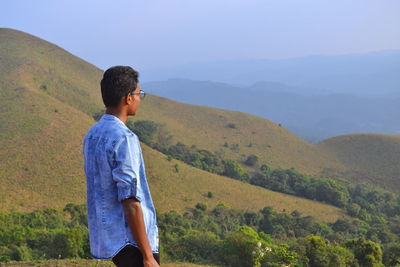 Young man looking at mountains against sky