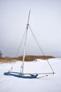 Sailboat on snow covered land against sky