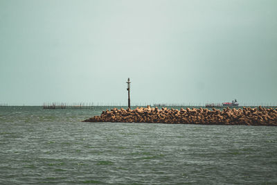 Lighthouse by sea against clear sky