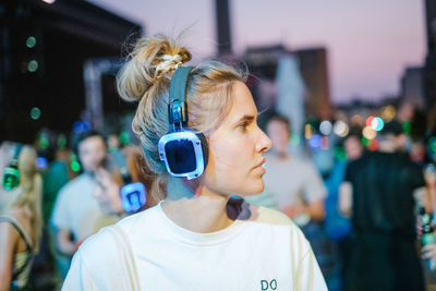 Portrait of woman wearing headphones in city