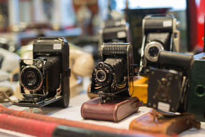 Antique black folding cameras with bellows on a shelf.