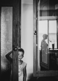 Portrait of boy looking through glass door