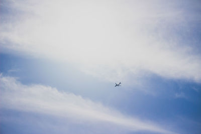 Low angle view of airplane flying against cloudy sky