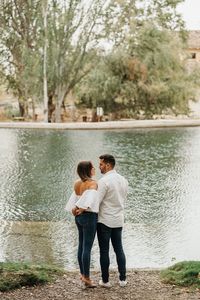 Rear view of friends standing by trees at shore
