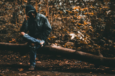 Man sitting on log in forest