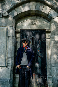 Full length portrait of young man standing against wall