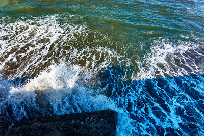 High angle view of sea waves splashing on rocks