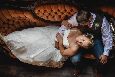 Portrait of smiling bride with groom relaxing on sofa at home