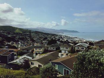 Cityscape by sea against sky